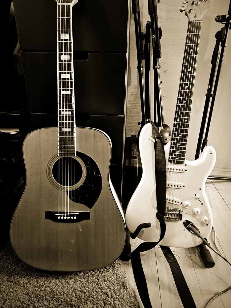 Acoustic guitar and a white Stratocaster on stands